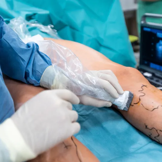 Jambe d'un patient au bloc opératoire avec un chirurgien.