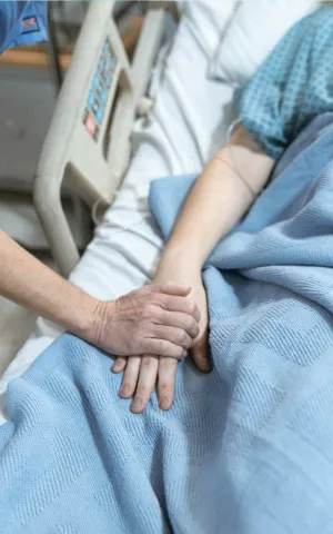 Une infirmière tient la main d'un patient allongé dans un lit