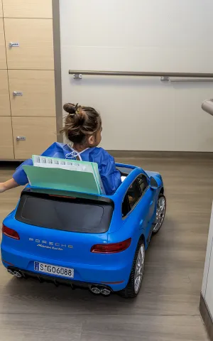 Enfant qui se rend au bloc opératoire en mini voiture