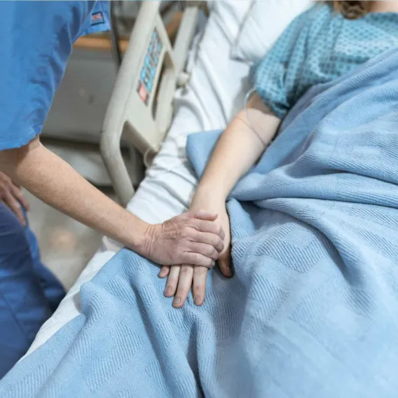 Une infirmière tient la main d'un patient allongé dans un lit
