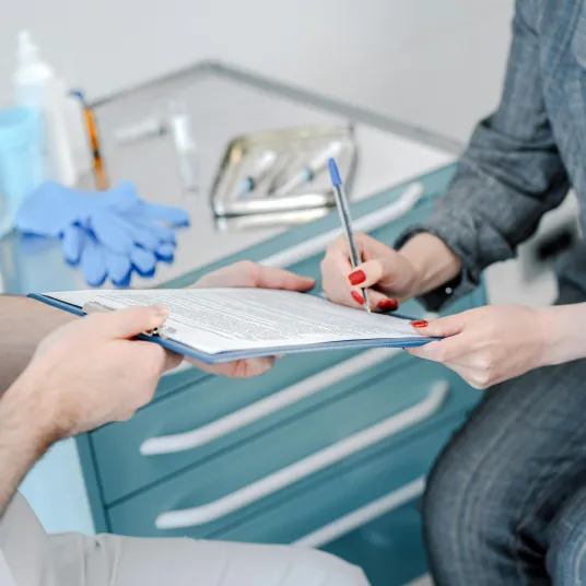 Une patient en train de remplir des documents médicaux à l'aide d'une infirmière