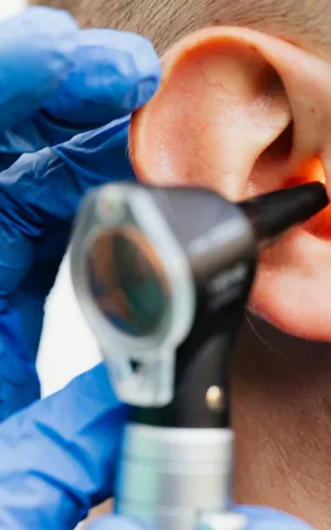Praticien avec un otoscope dans l'oreille d'un patient en consultation ORL.