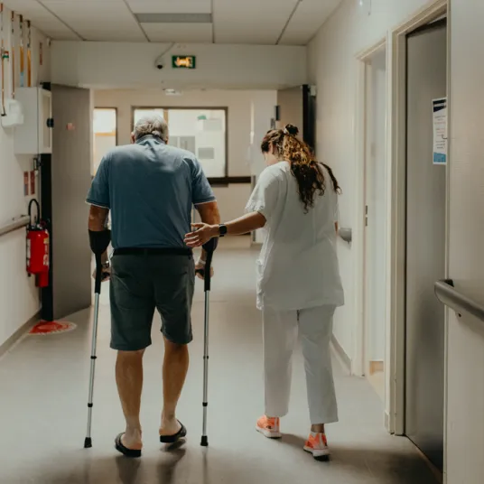 Kiné et patient qui marchent dans le couloir