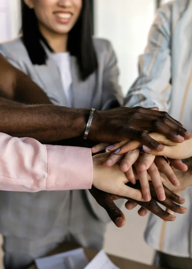 Groupe de personne regroupant leur main ensemble en signe de cohésion et de travail d'équipe.