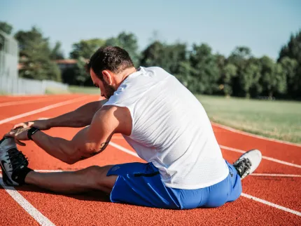 Homme s'étirant les jambes sur une piste d'athlétisme