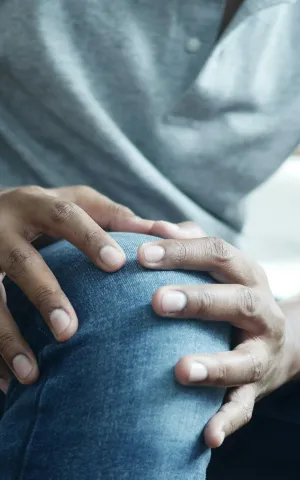 Zoom sur une personne touchant son genou avec ses deux mains à cause de la douleur - Groupe Vivalto Santé