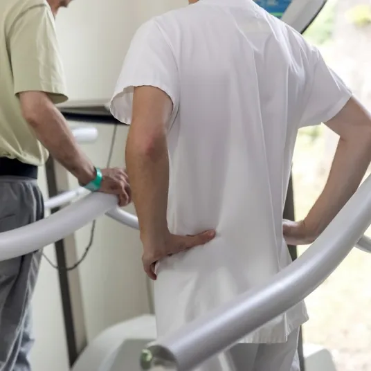 Un kiné parle à un patient sur un tapis de course