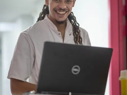Infirmier devant un ordinateur avec un grand sourire
