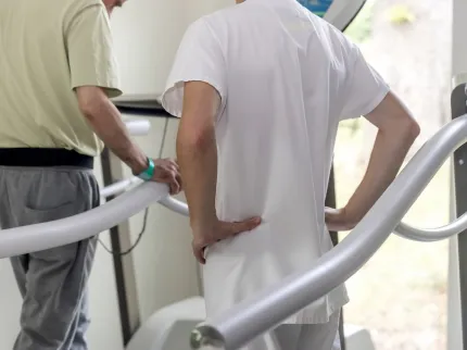 Un kiné parle à un patient sur un tapis de course