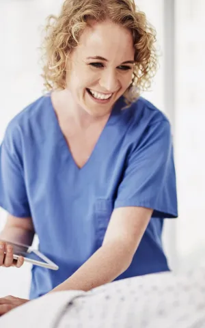 Infirmière souriant à un patient alité, Groupe Vivalto Sante