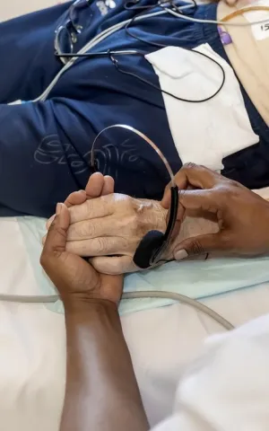 Une infirmière tient la main d'un patient allongé dans un lit