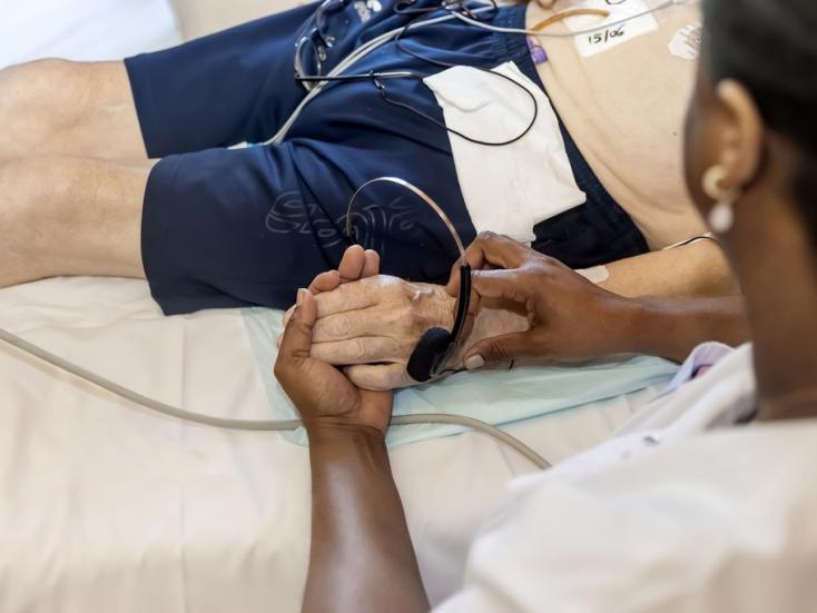 Une infirmière tient la main d'un patient allongé dans un lit