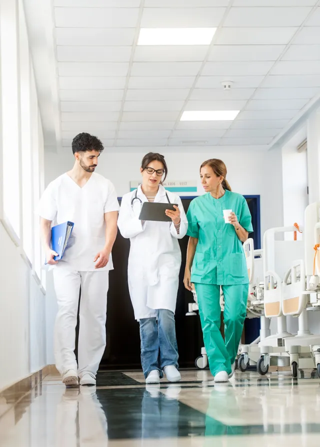 Equipe médicale de trois personnes marchant dans les couloir d'un hôpital, Groupe Vivalto Santé