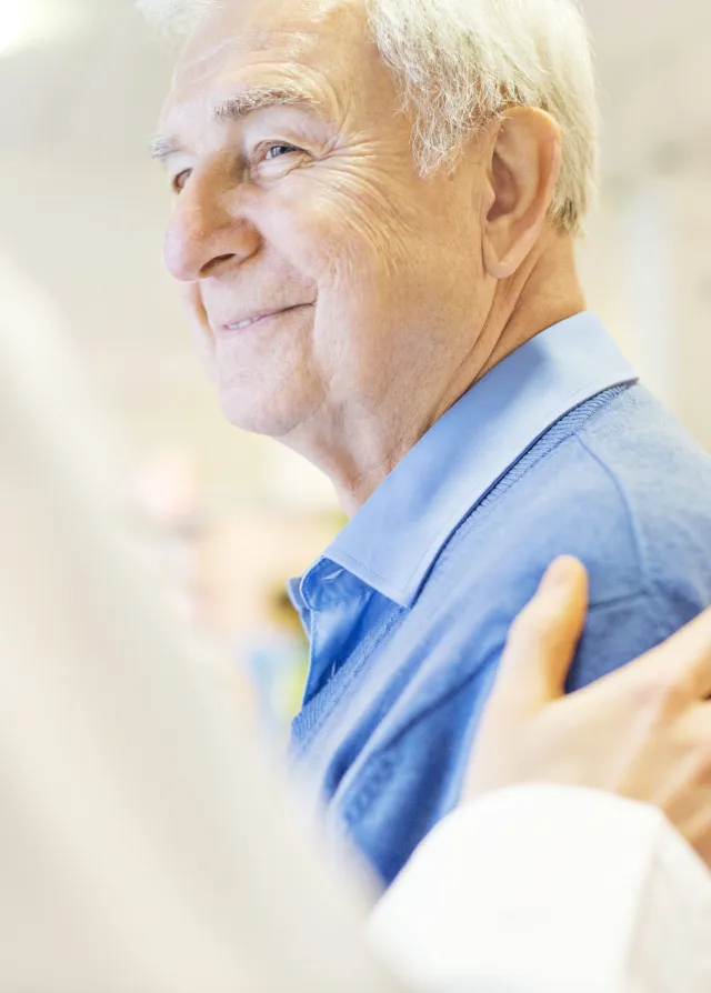 Patient agé souriant au médecin qui lui touche l'épaule en signe d'empathie, Groupe Vivalto Santé