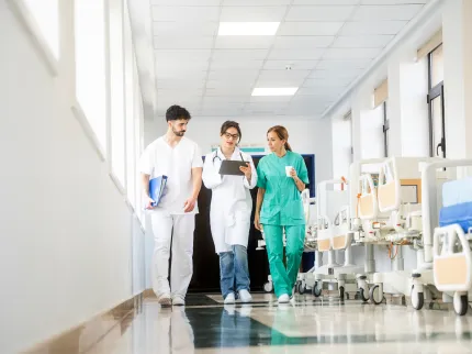 Equipe médicale de trois personnes marchant dans les couloir d'un hôpital, Groupe Vivalto Santé