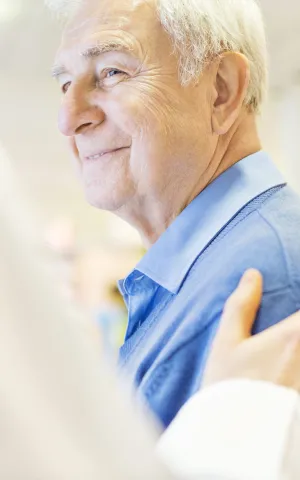 Patient agé souriant au médecin qui lui touche l'épaule en signe d'empathie, Groupe Vivalto Santé