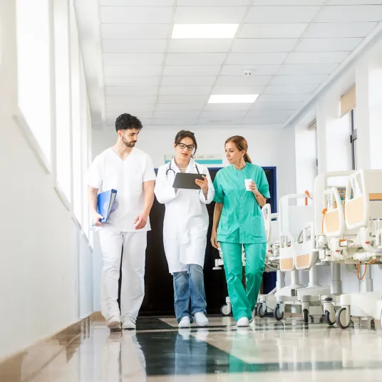 Equipe médicale de trois personnes marchant dans les couloir d'un hôpital, Groupe Vivalto Santé