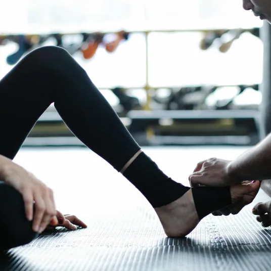 Un coach réalisant un soin sur le pied d'une jeune femme dans une salle de sport