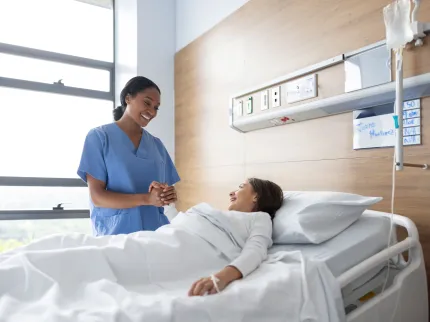 Infirmière tenant la main d'une patient alitée - Groupe Vivalto Santé