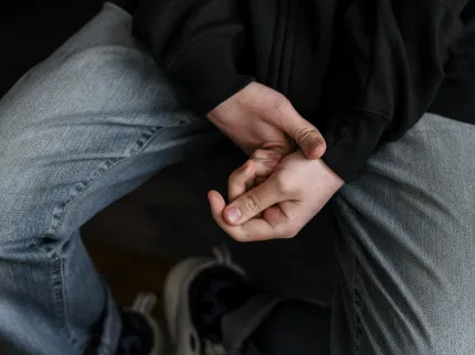 Zoom sur les mains et le corps d'un adolescent, l'air stressé, en thérapie.