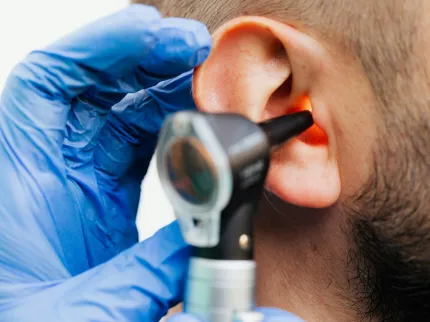 Praticien avec un otoscope dans l'oreille d'un patient en consultation ORL.