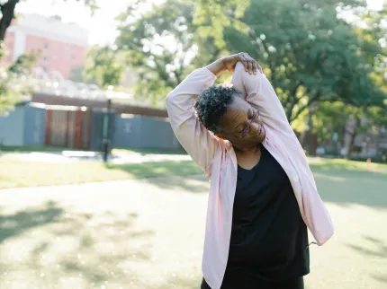 Femme âgée s'étirant le dos en se touchant le coude - Groupe Vivalto Santé