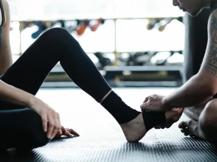 Un coach réalisant un soin sur le pied d'une jeune femme dans une salle de sport