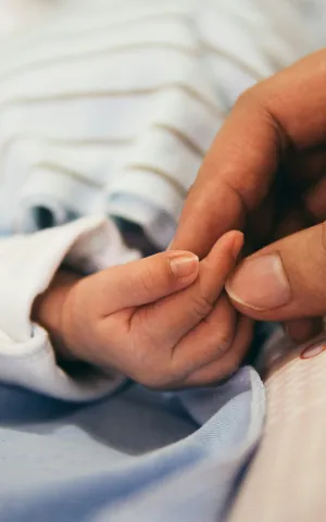 Zoom sur la main d'une mère touchant la main de son nouveau né - Groupe Vivalto Santé