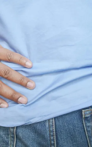 Zoom sur un homme se tenant le bas du dos en signe de douleur