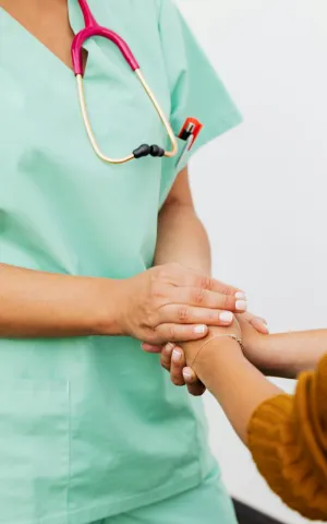 Une infirmière en vert tenant la main d'un patient de manière bienveillante