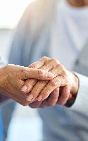 Une soignante tient la main d'une personne âgée