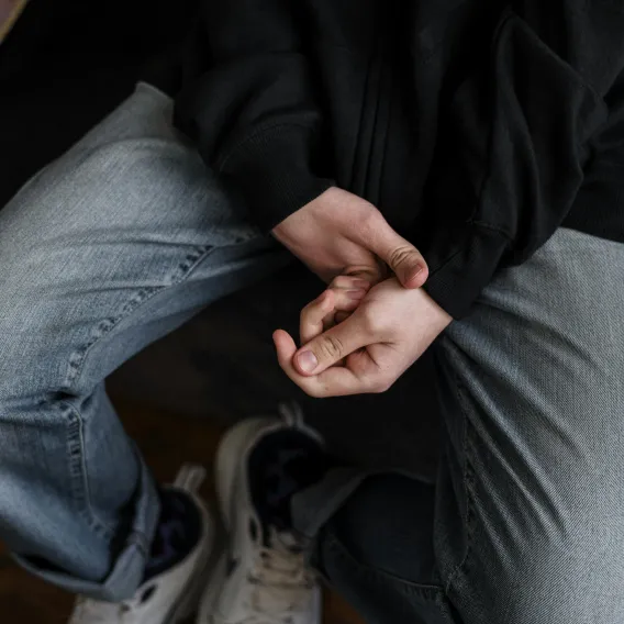 Zoom sur les mains et le corps d'un adolescent, l'air stressé, en thérapie.