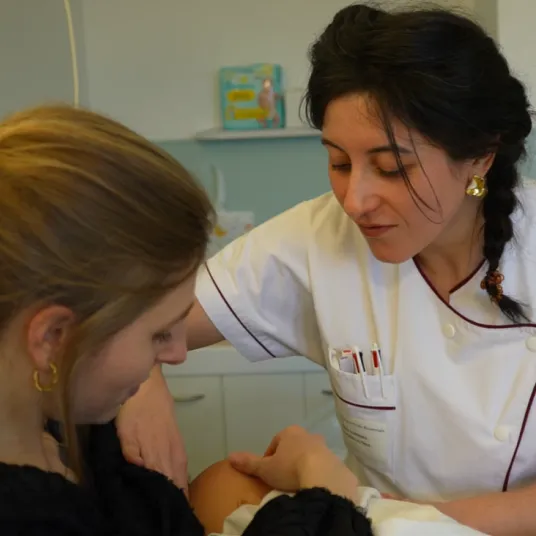 soignante qui sourit avec maman qui allaite