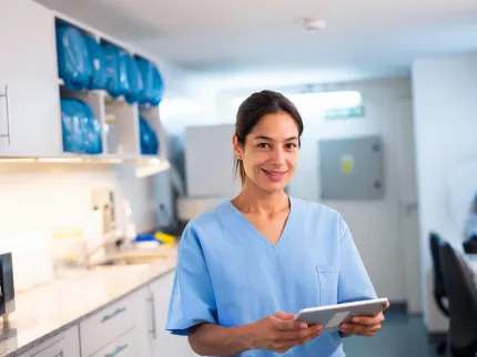Une infirmière souriant avec une tablette dans les mains, Groupe Vivalto Santé
