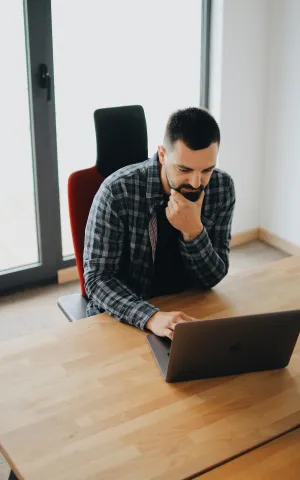 Un homme sur son ordinateur en train de simuler ses revenus avant de compléter son installation en libéral. 