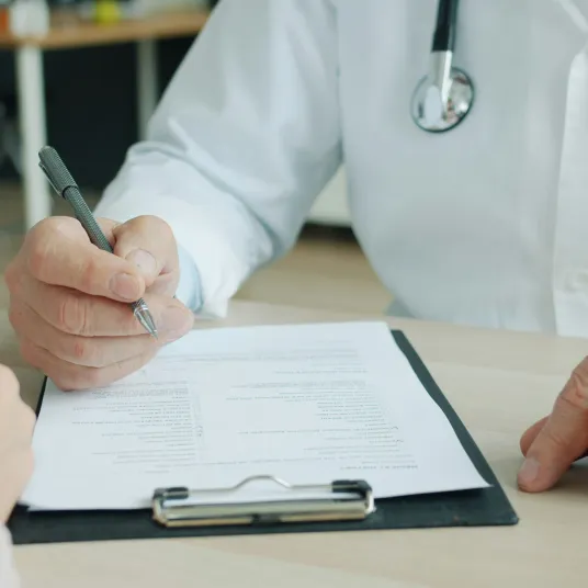 Un médecin remplissant des documents papiers avec son crayon