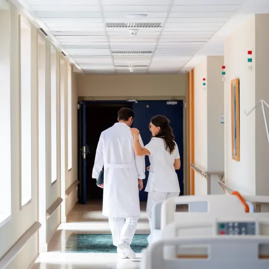 Un médecin et une infirmière marchant dans un couloir. Groupe Vivalto Santé