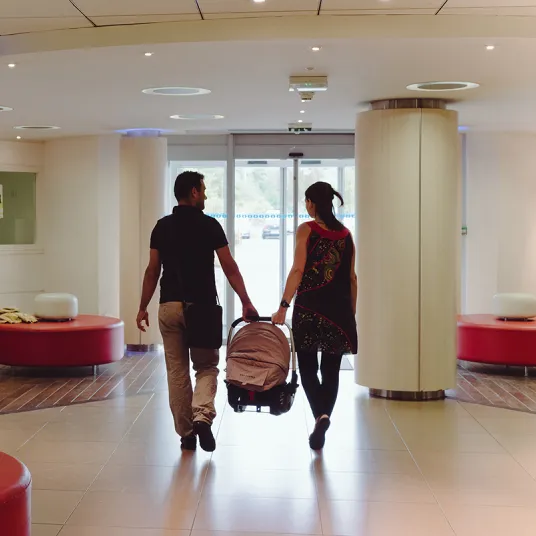 Des parents se dirigent vers la sortie de la Maternité avec le bébé après la naissance