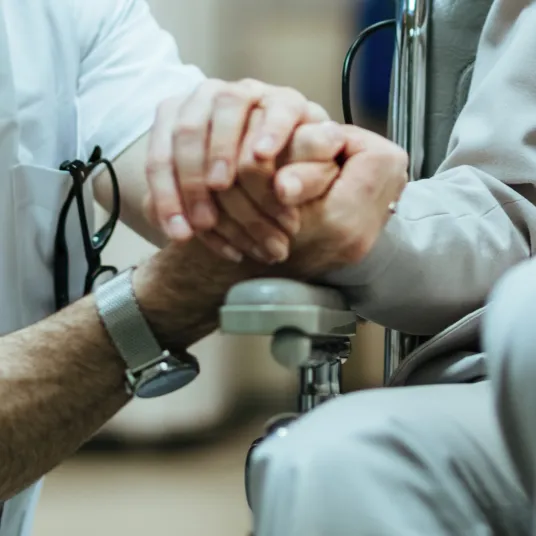 La main d'un soignant qui tient la main d'un patient