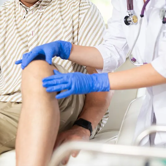 Orthopédiste examine le genou d'un pateint 