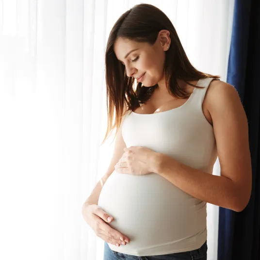 Une femme enceinte heureuse touche son ventre