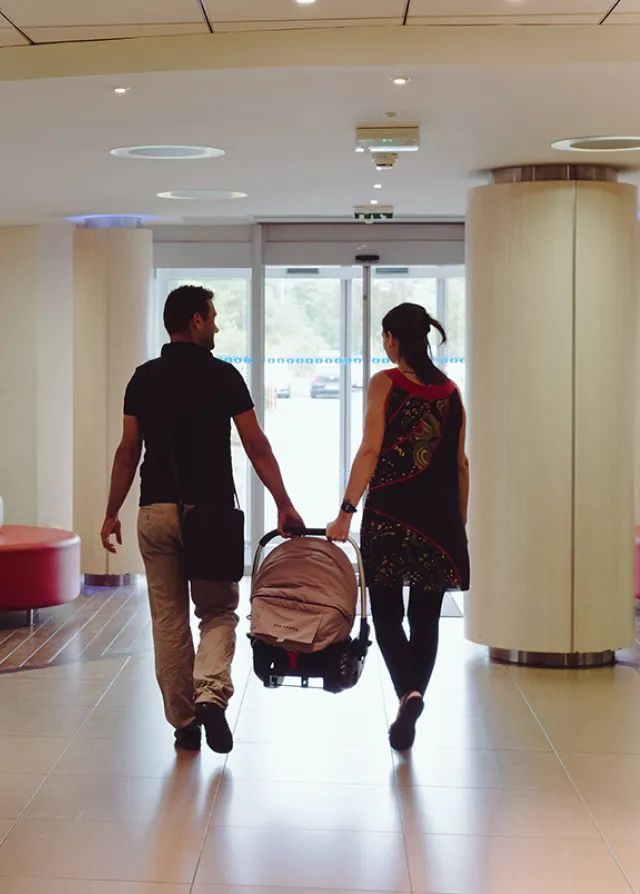 Des parents se dirigent vers la sortie de la Maternité avec le bébé après la naissance