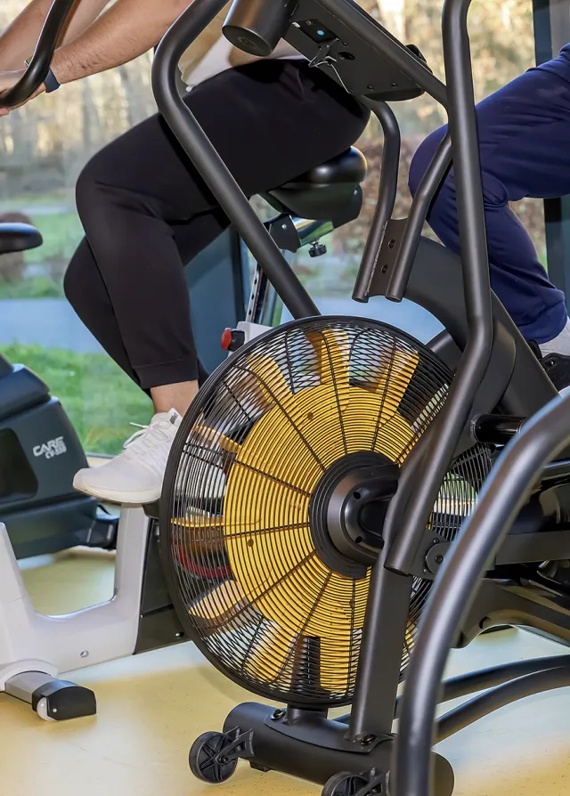 Patient qui fait du vélo dans la salle de sport du SMR