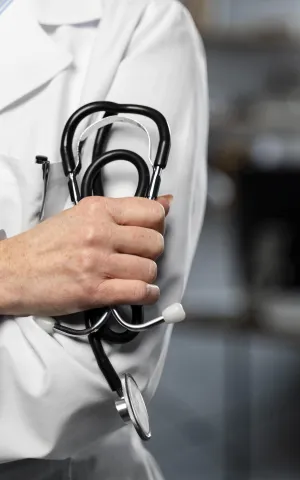 Médecin tient un stéthoscope dans la main et croise les bras