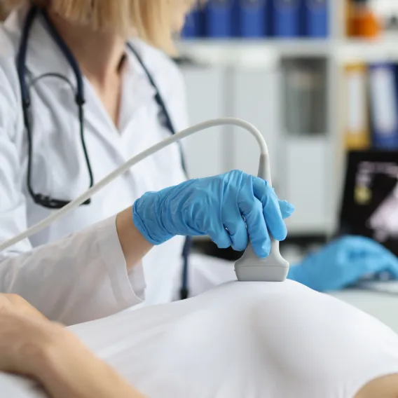 Gynécologue réalisant une échographie mammaire sur une patiente allongée sur sa table d'examen