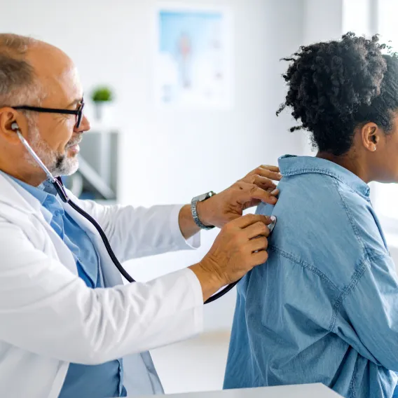 Un pneumologue place un stéthoscope dans le dos d'un patient lors d'une consultation médicale