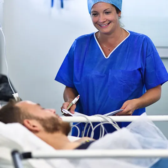 Aide soignante accompagnant un patient alité. Groupe Vivalto Santé