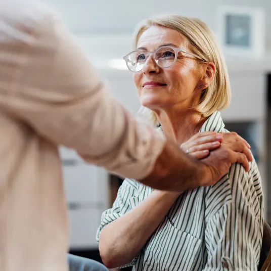 Patiente âgée avec la main de son docteur sur l'épaule.