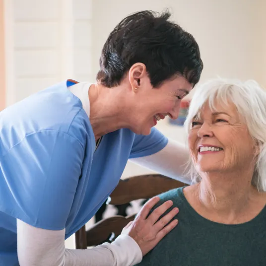 Une infirmière et sa patiente en train d'échanger des sourires.