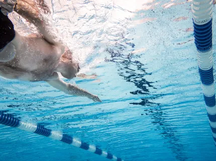 Homme nageant dans une piscine avec un sac de stomie - Vivalto Dom